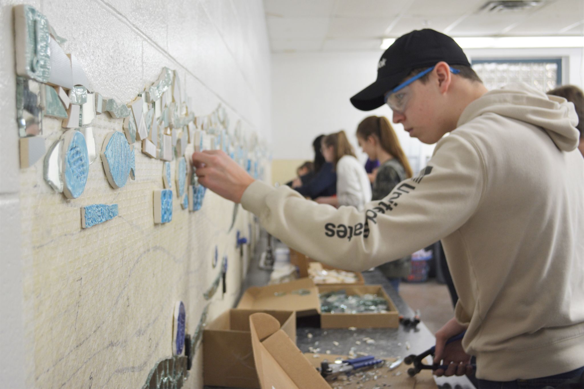 Students adding tile to the wall