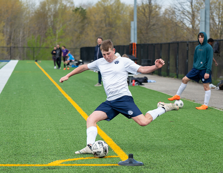 male student kicking soccerball
