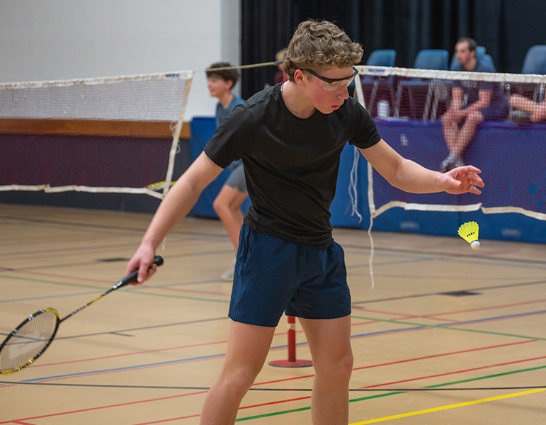 male student hitting badminton