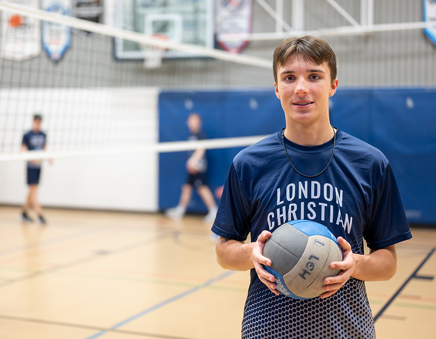 male student holding volleyball