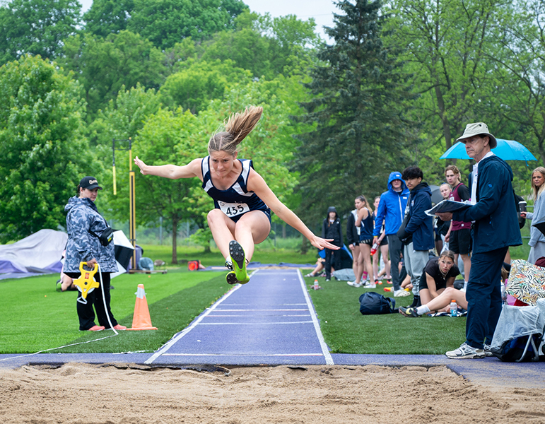 female student making long jum in track and field