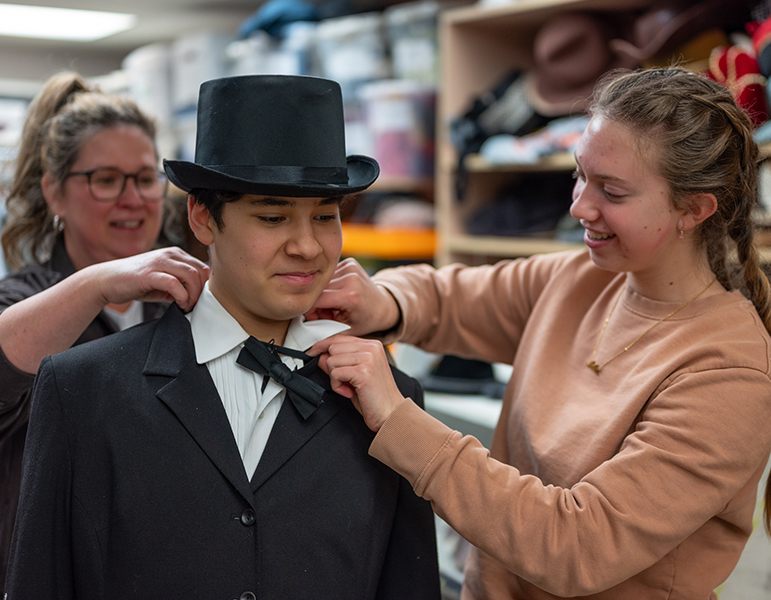 Two students fixing actor's costume back stage