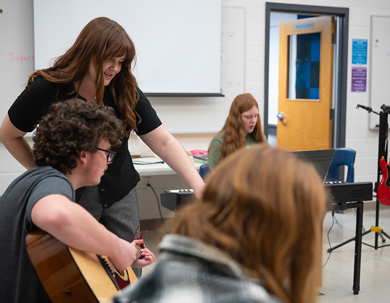 teacher helping guitar students
