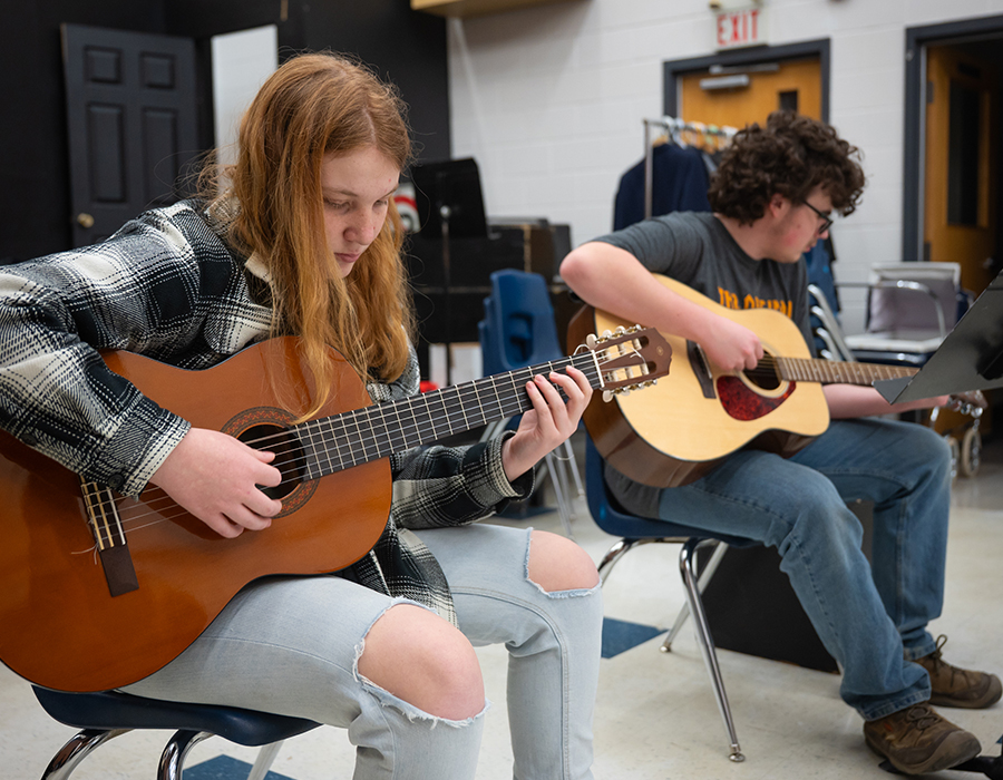two students playing guitar